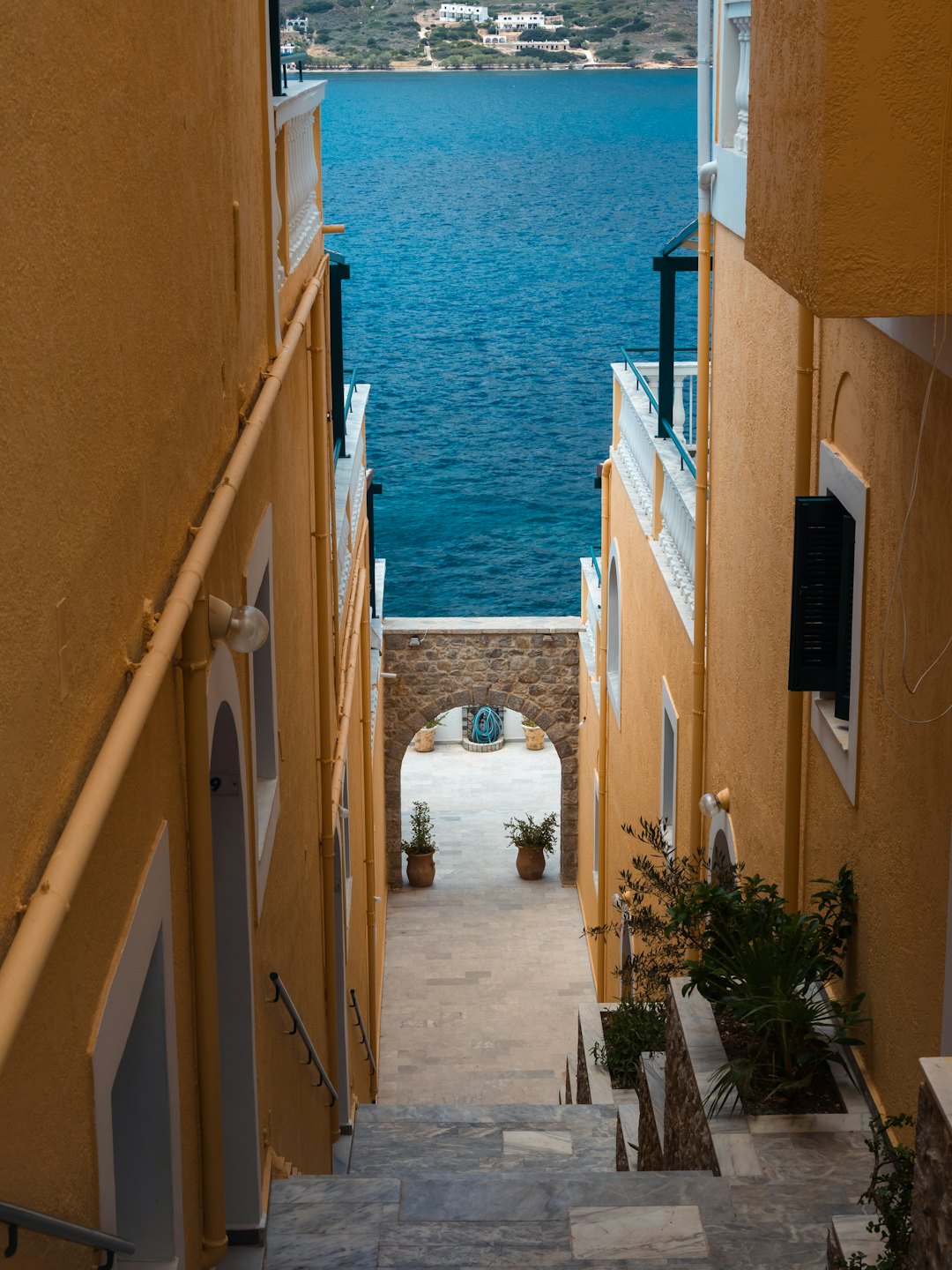 Scalini di pietra conducono oltre un arco rustico verso il mare.