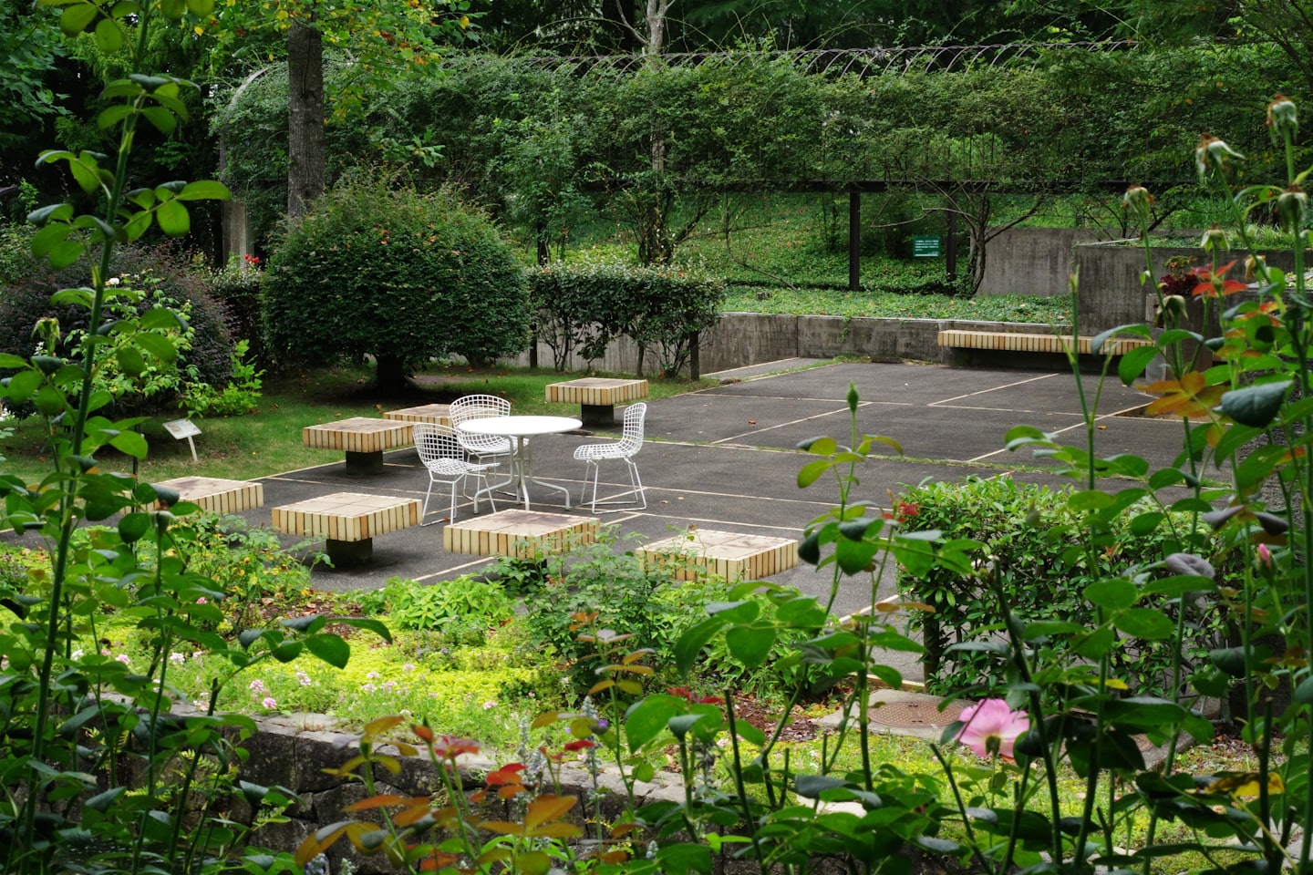 Mobili in metallo bianco su un patio circondato dal verde del giardino.